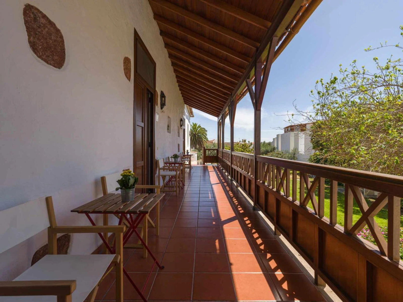 Balconada común con mesas y sillas frente a las casas. · Casa Rural La Montañeta