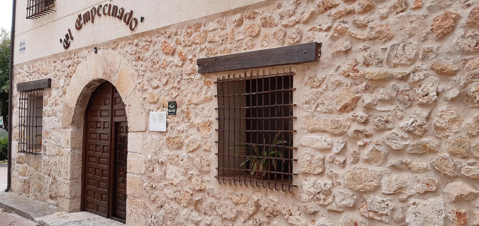 Fachada de piedra y entrada señalizada de El Empecinado · Casa Rural El Empecinado