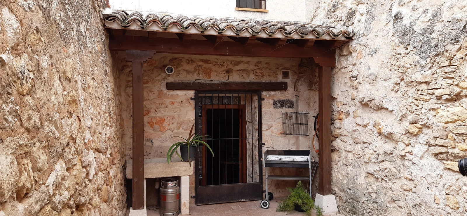 Patio de El Empecinado con barbacoa bajo el porche · Casa Rural El Empecinado