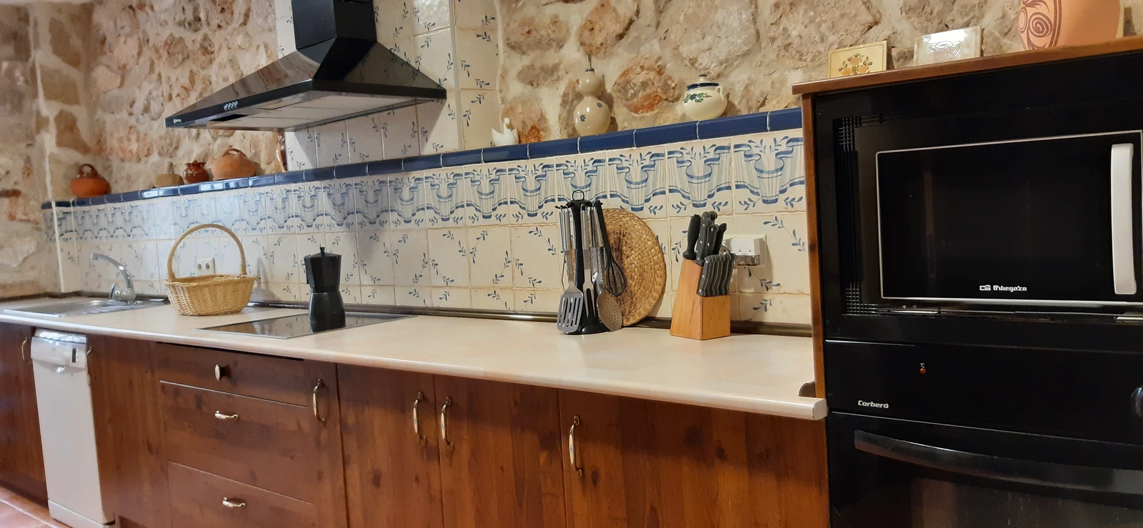 Cocina común con encimera, horno y microondas · Casa Rural El Empecinado