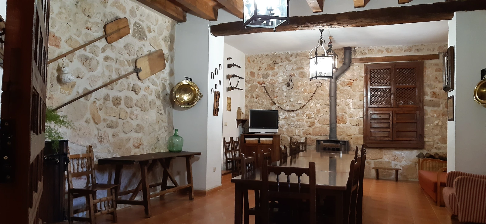 Comedor común con mesas castellanas y estufa · Casa Rural El Empecinado