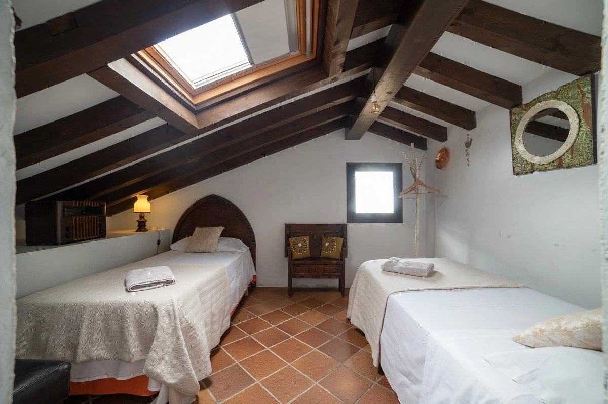 Dormitorio de buhardilla con dos camas individuales y ventana de techo. · El Pósito de Hita