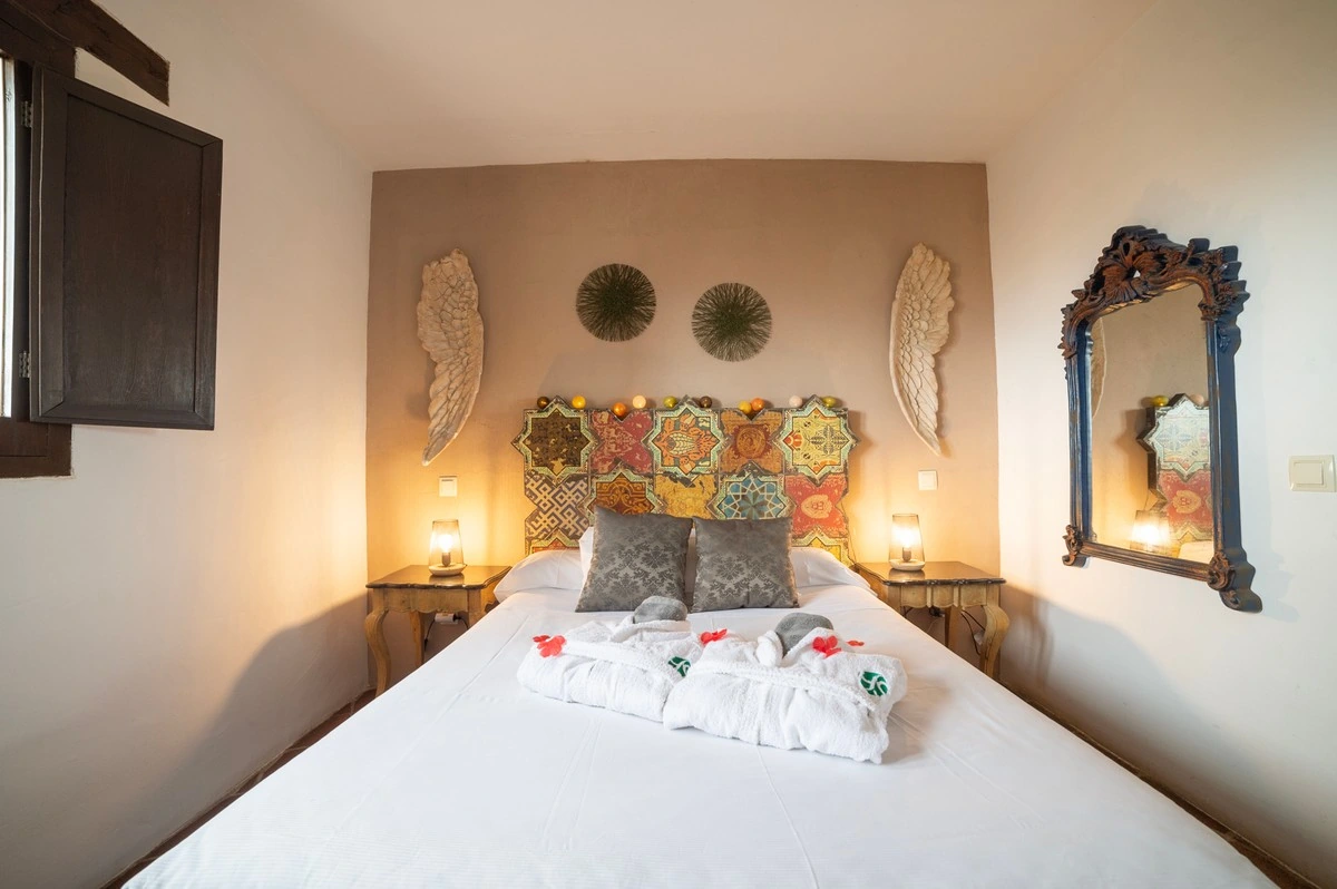 Dormitorio con cama doble y cabecero de motivos geométricos de colores. · El Pósito de Hita