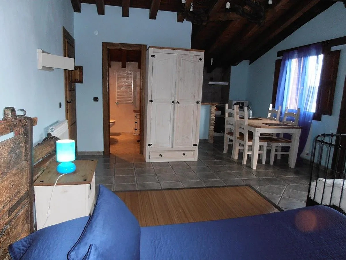 Apartamento III: cama, mesa de comedor y puerta del baño · Alojamientos Rurales Eras Altas