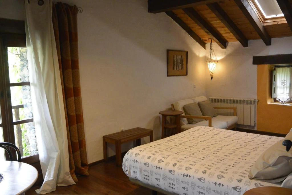 Dormitorio bajo vigas de madera con zona de estar · La Casa del Sol