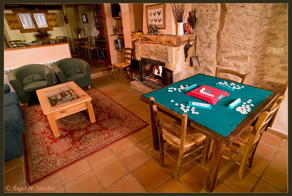 Salón compartido con chimenea, sillones y mesa de juegos, junto al comedor. · Las Trojes