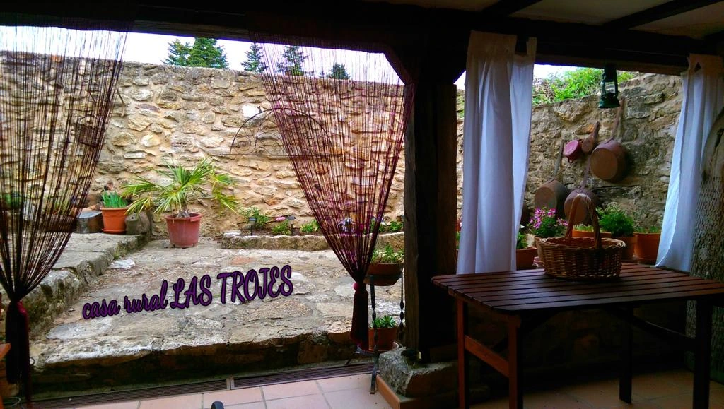 Rincón cubierto junto al patio de Las Trojes, con mesa y plantas. · Las Trojes