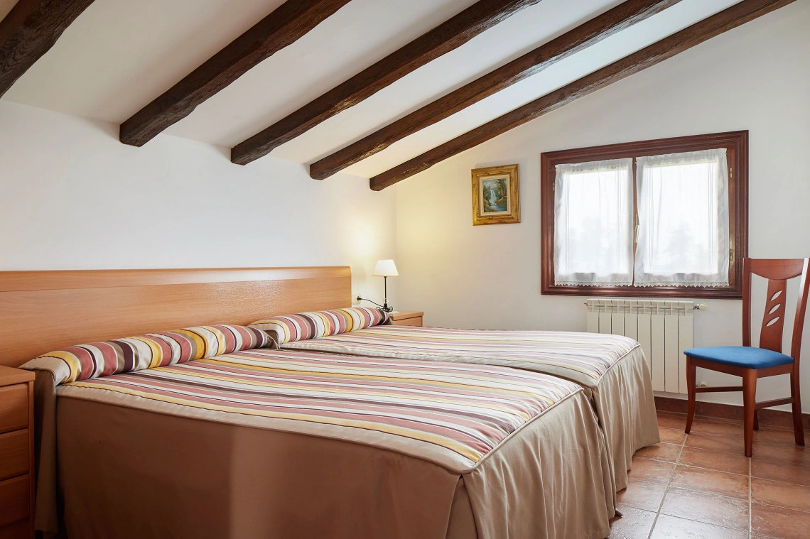 Dormitorio de Mendi con dos camas bajo vigas de madera · Epotx Etxea