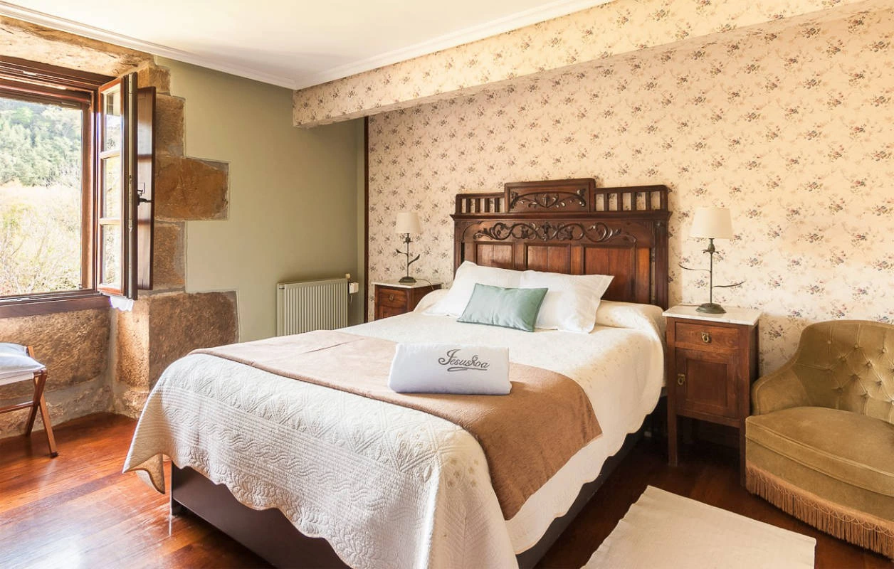 Dormitorio con cama doble y cabecero de madera tallada; habitación sin nombre publicado. · Jesuskoa