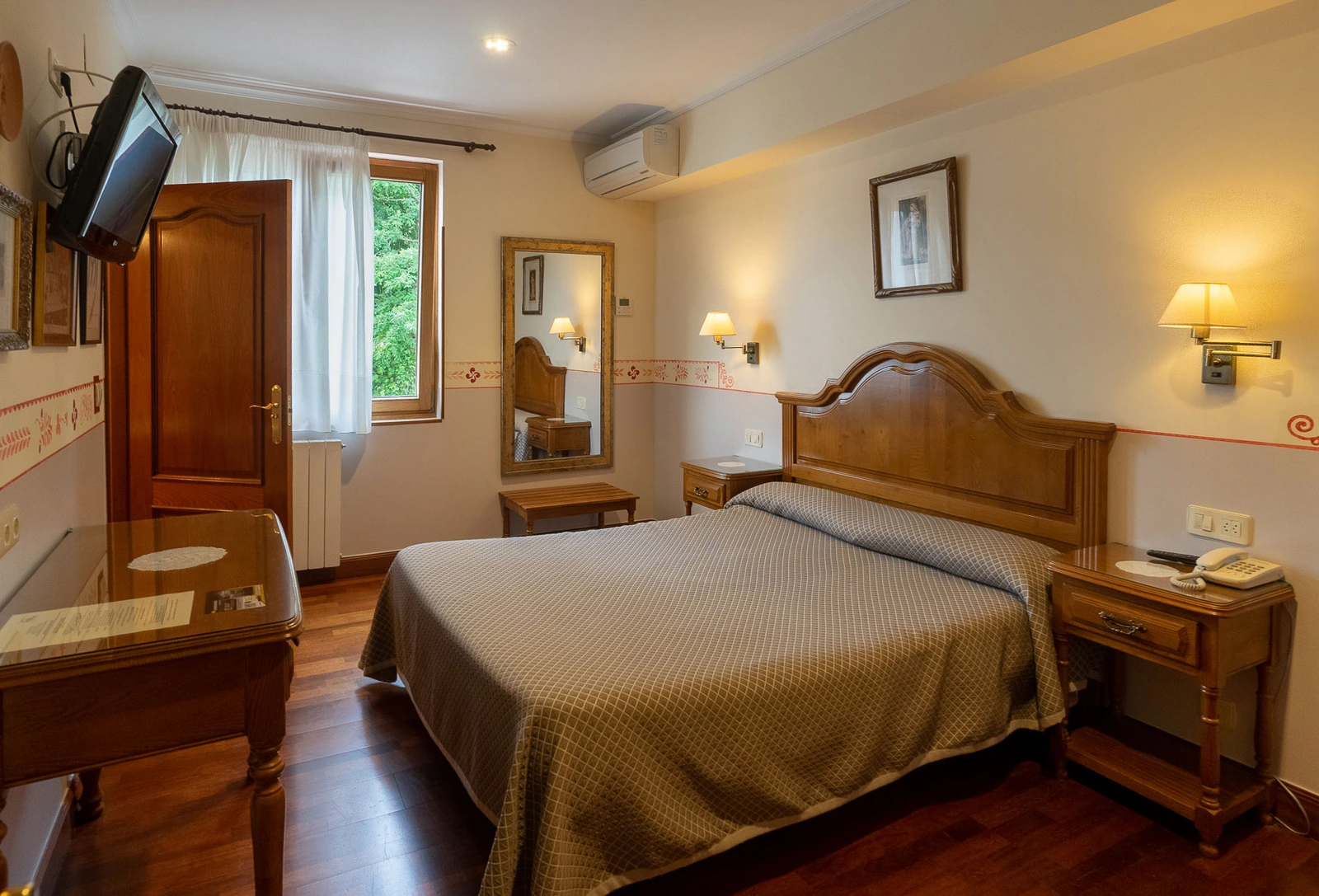 Dormitorio con cama de matrimonio y mobiliario de madera. · Hotel Leku Eder