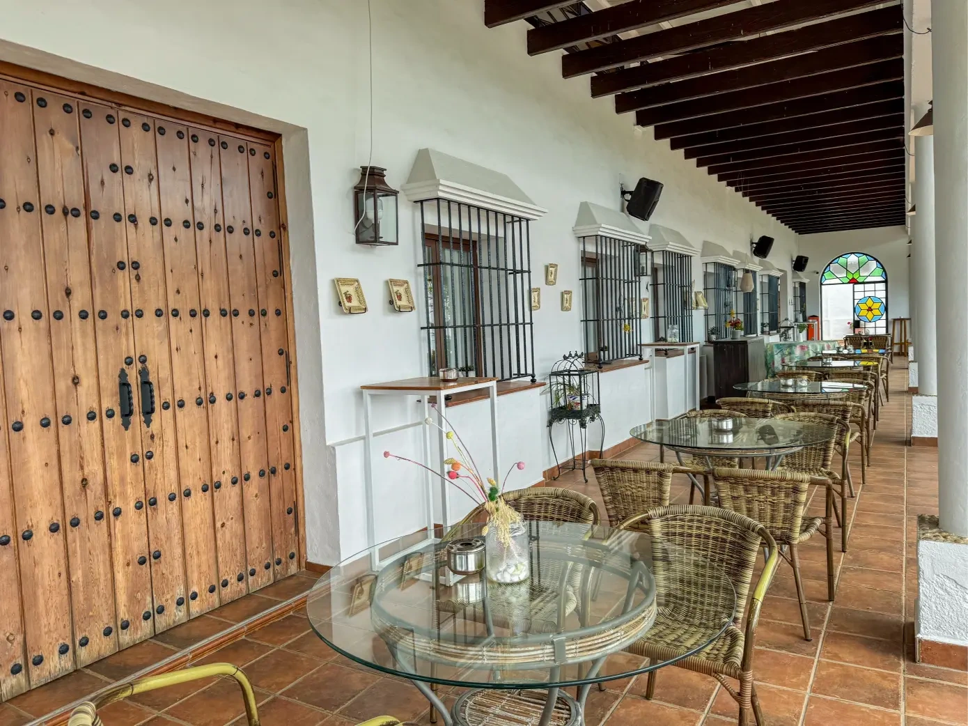 Galería cubierta con mesas junto al patio del hotel · Hotel Valsequillo