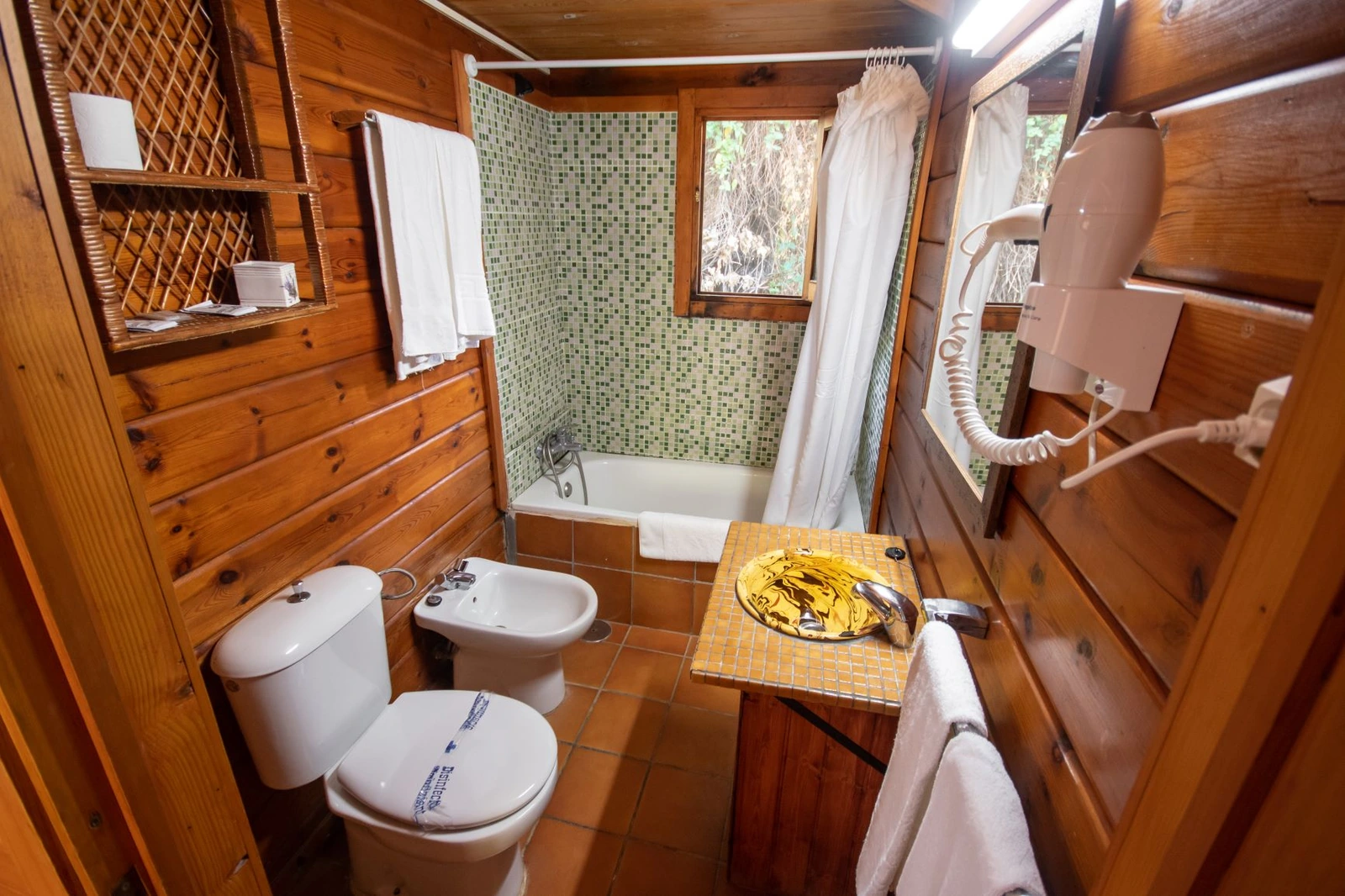 Baño de una cabaña de madera con bañera y lavabo · Posada de Cortegana