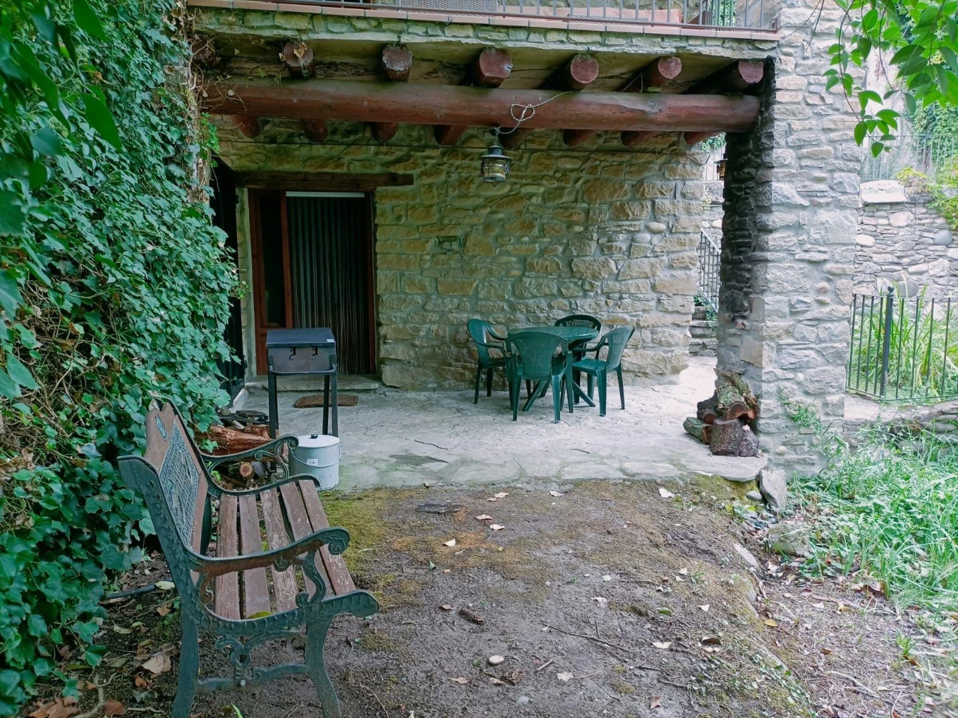 Porche cubierto de piedra del bungalow, con una mesa para comer al aire libre.