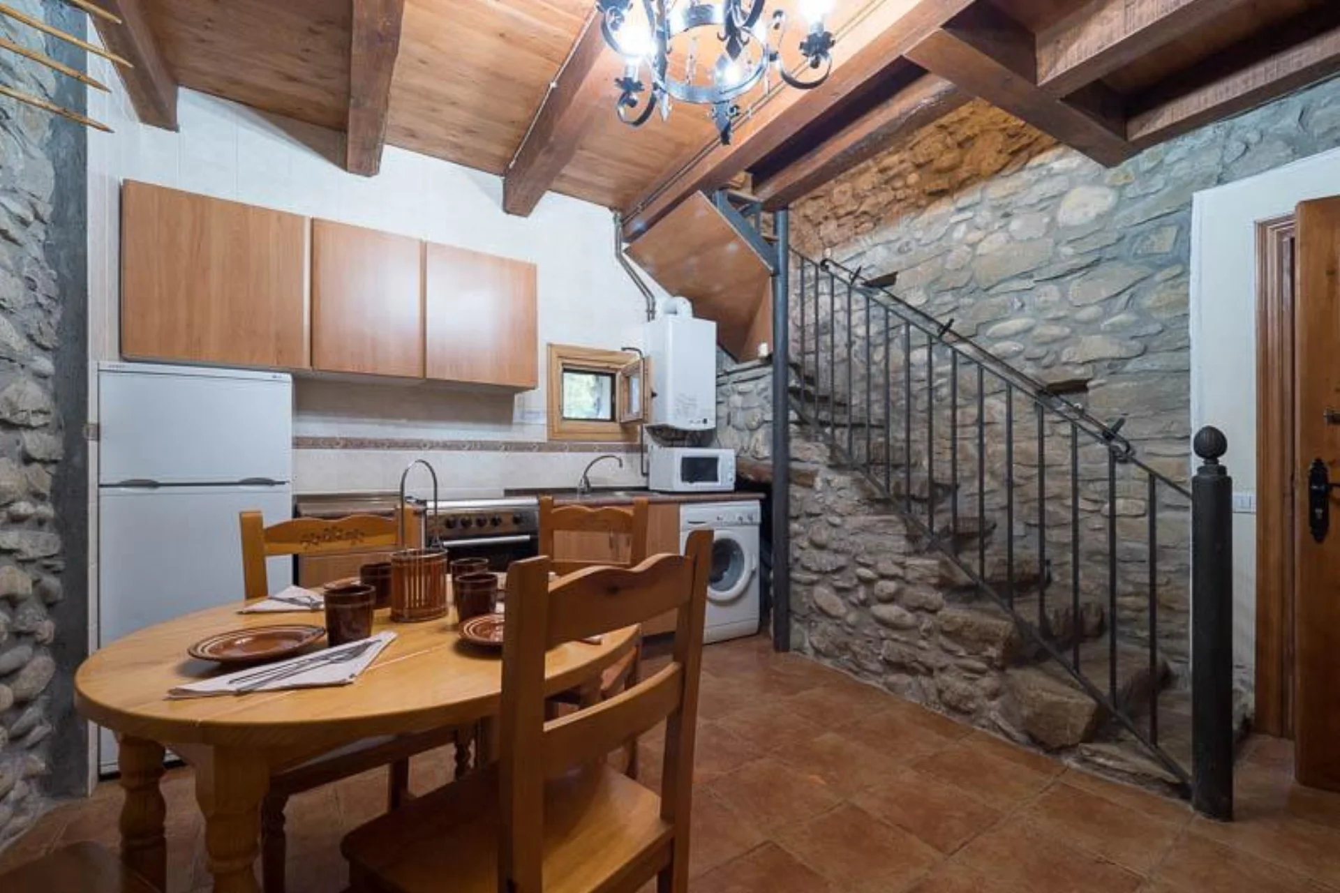 Cocina-comedor del bungalow con escalera de madera a la planta superior.