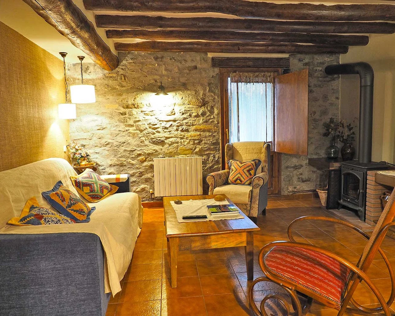 Salón con mobiliario tradicional y paredes de piedra de Casa Lanau