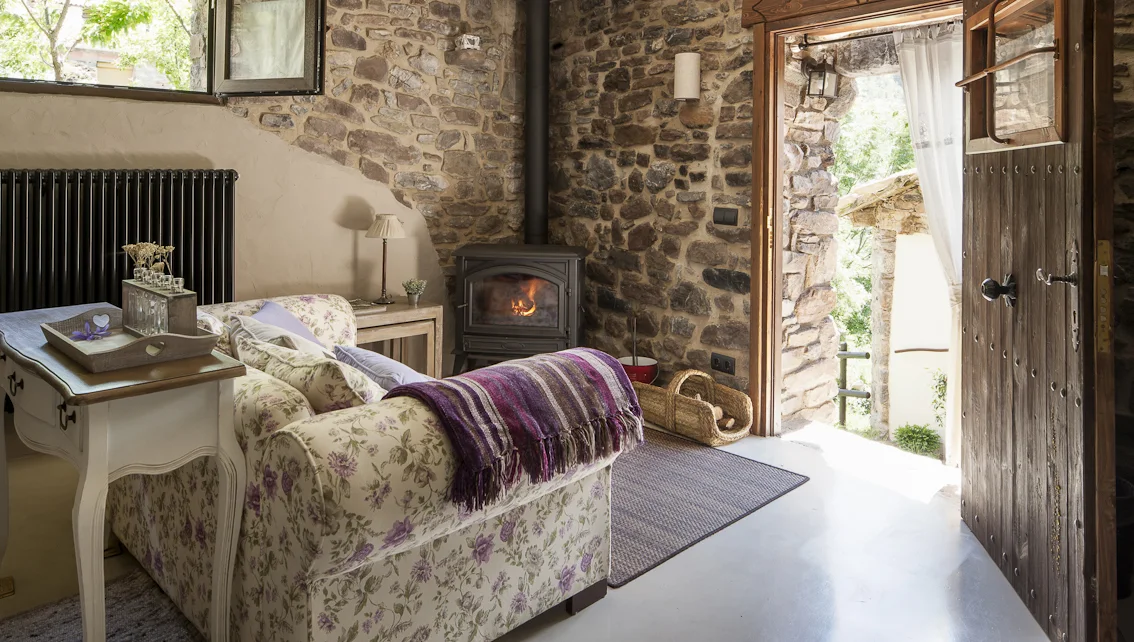 Salón de El Acebo de Casa Muria con chimenea y vigas de madera