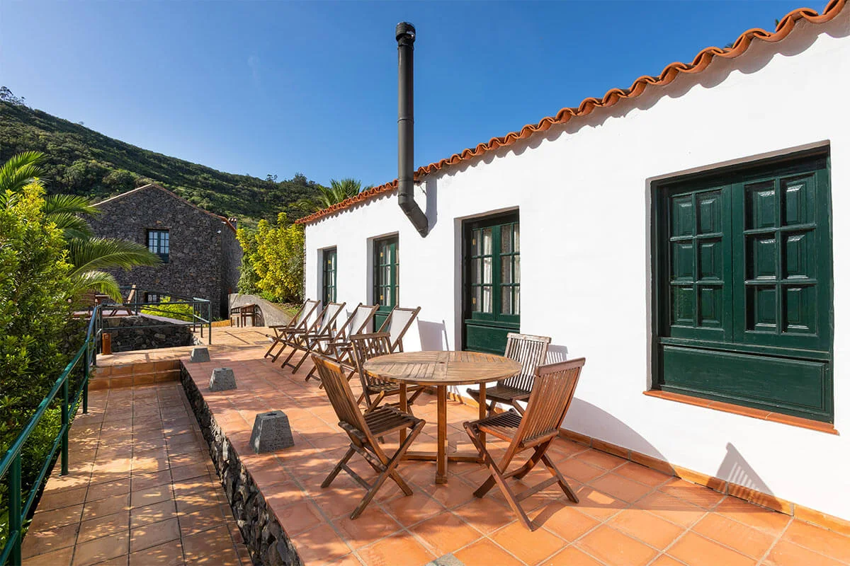 Fachada de piedra entre la vegetación en Las Casas del Chorro