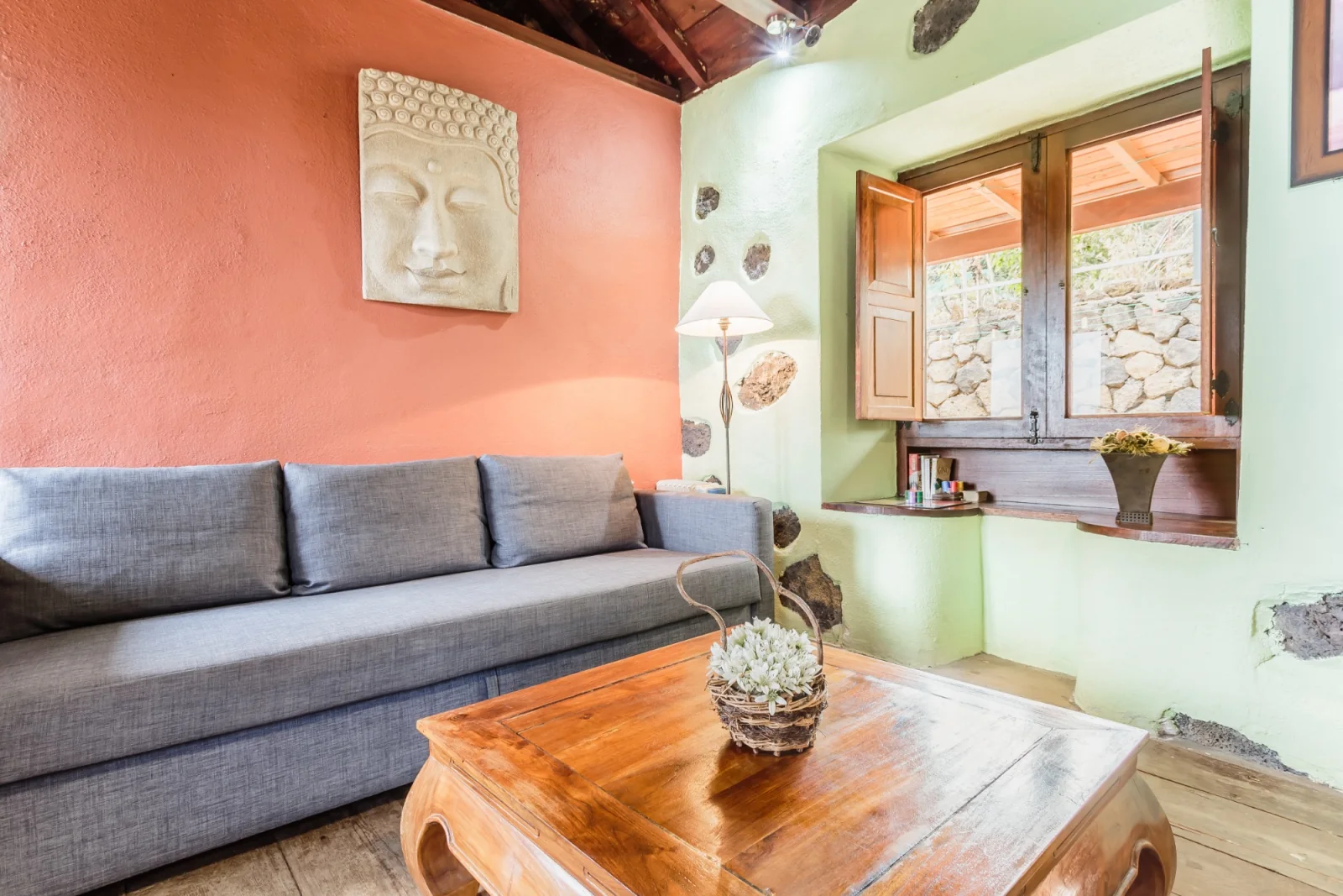 Salón con sofá, techo de madera y paredes de piedra