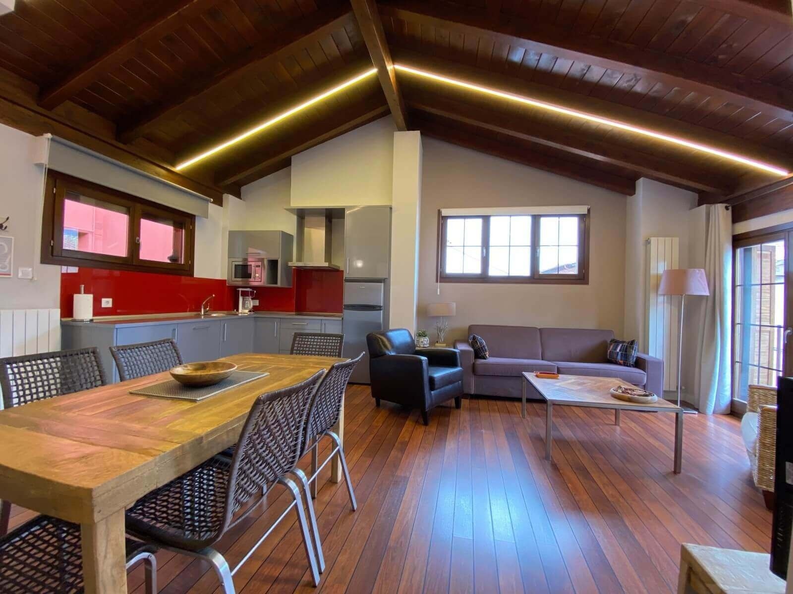 Salón y cocina bajo vigas de madera de Apartamentos Ezcaray