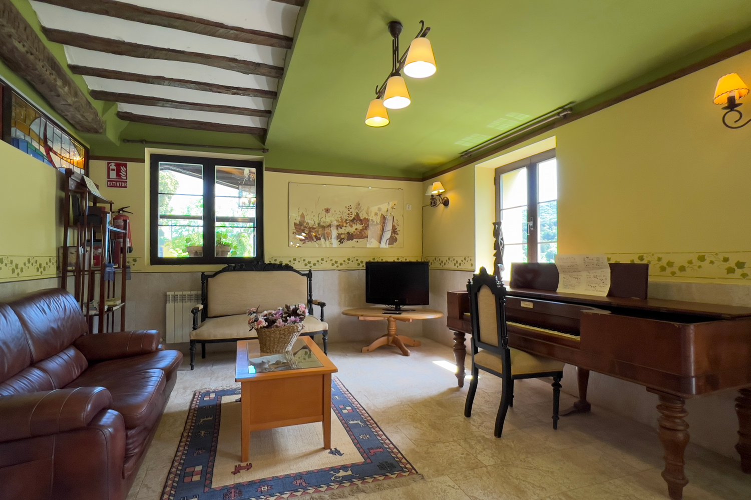 Salón de Casa Rural La Calera con piano y sofás