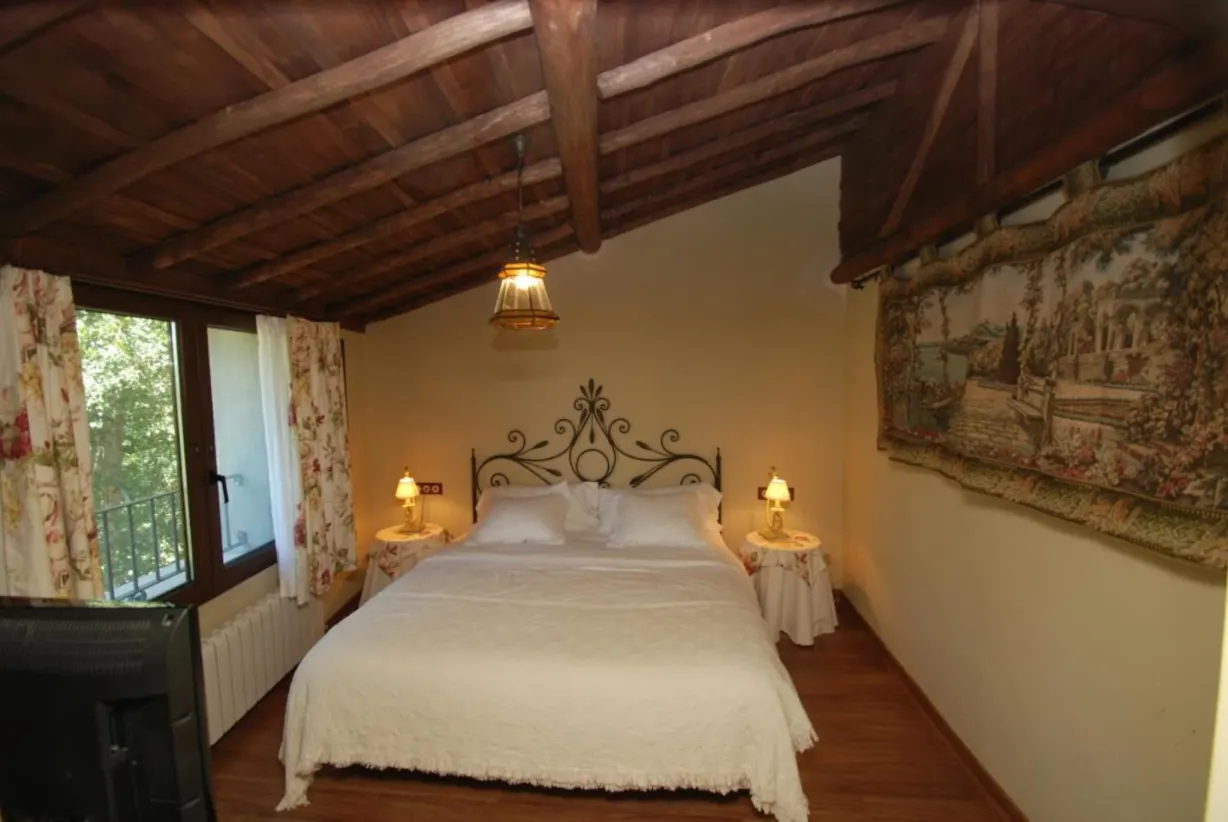 Dormitorio doble con techo de madera y balcón