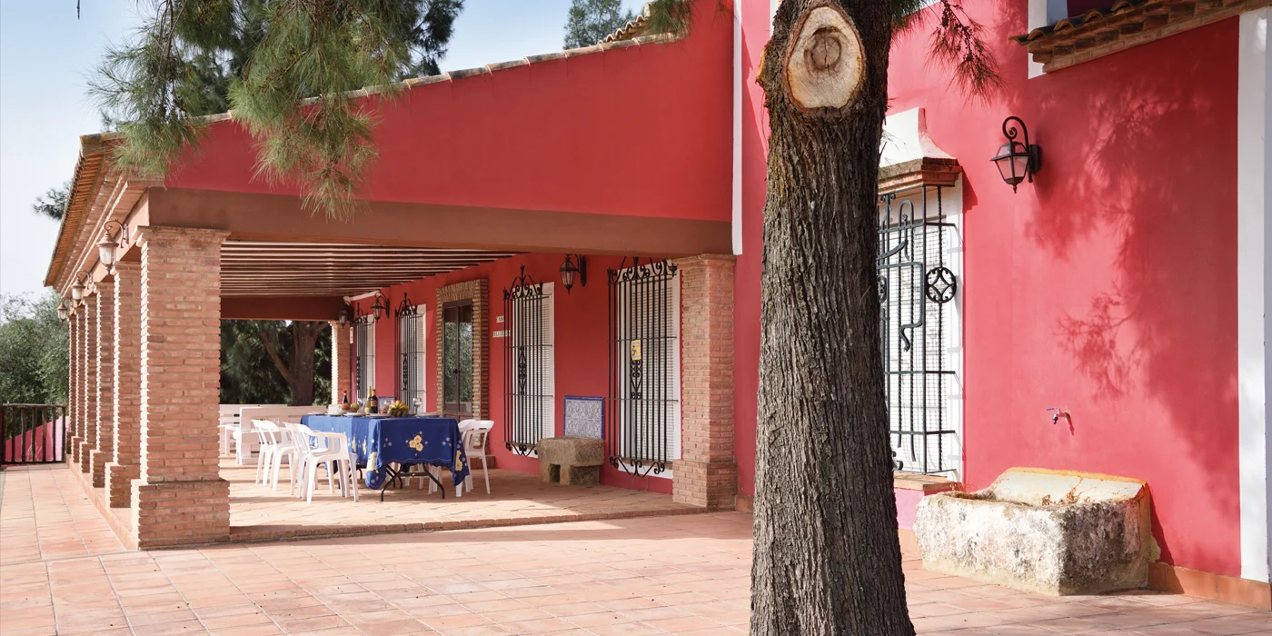 Fachada roja y terraza cubierta de El Silgueiro