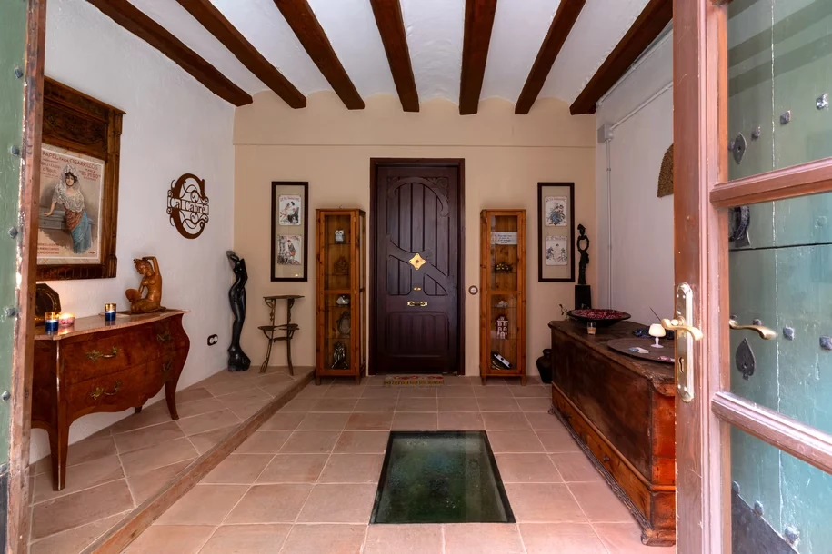 Vestíbulo de Cal Cabré del Priorat con puerta de madera y mobiliario antiguo