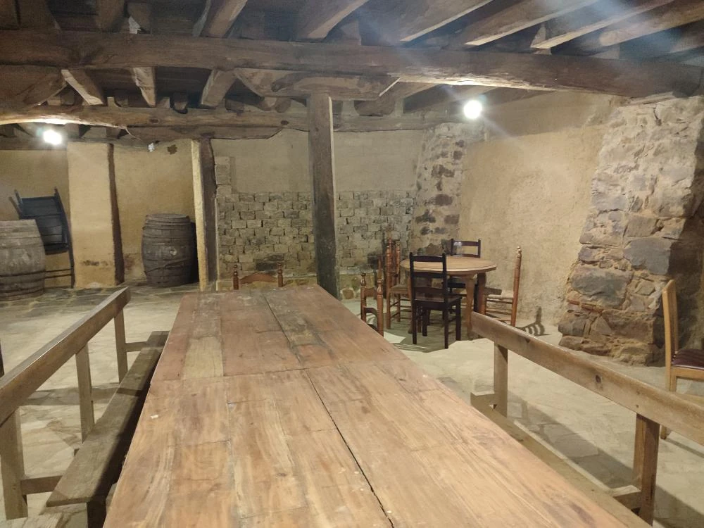 Bodega rehabilitada con mesas y bancos en Casa Rural La Paloma